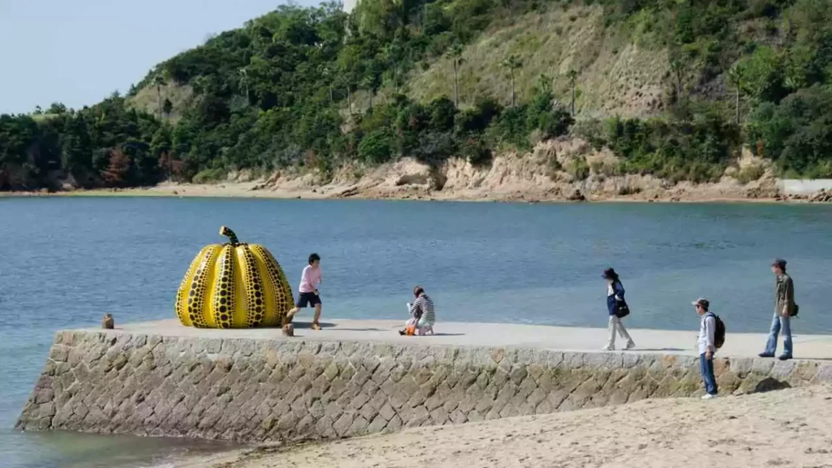 Conheça os melhores lugares para visitar no japão - escultura de abóbora gigante com pessoas fotografando e brincando ao redor, em ilha de Naoshima
