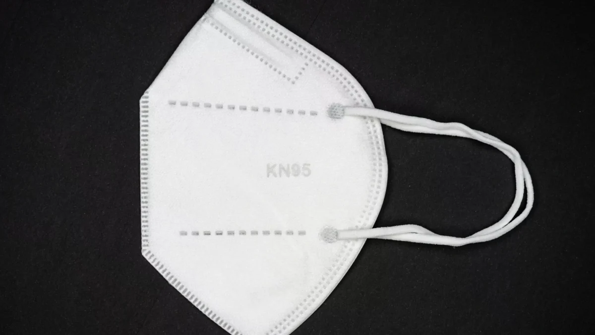 Máscara n95, dobrada e mostrada de lado, num fundo preto. A máscara segura para viajar de avião na pandemia.