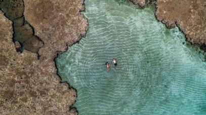 Foto da vista de cima de um casal boiando nas piscinas naturais da Península de Maraú.