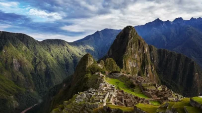 Peru, Machu Picchu à frente, entre outras montanhas, com céu nublado.