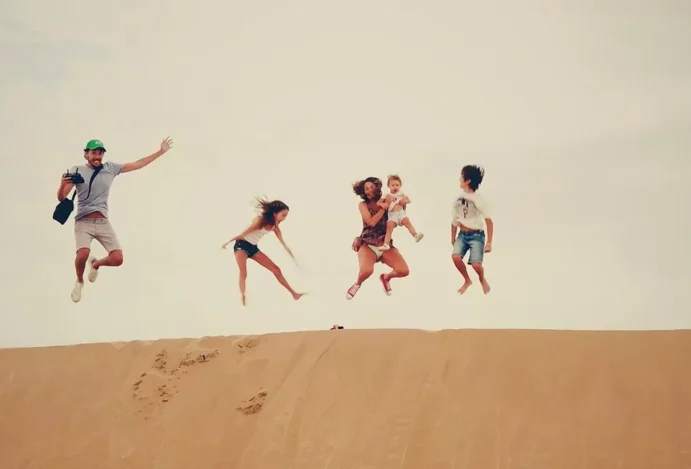 Família pula para clique da câmera. Viajar com crianças.